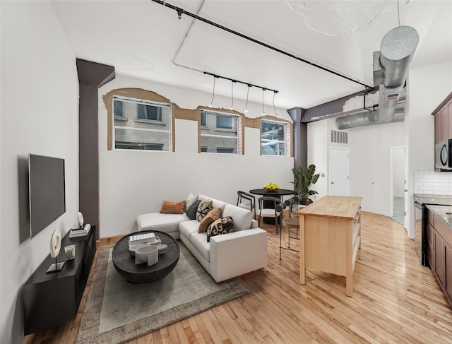 living area with rail lighting, light wood-style flooring, and visible vents