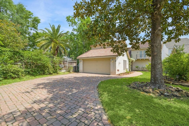 view of front of property featuring a tile roof, a front yard, a garage, decorative driveway, and fence