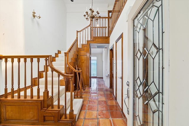 foyer entrance featuring stairs, a high ceiling, and a chandelier