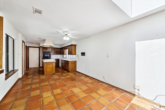 kitchen with ceiling fan, visible vents, a skylight, a center island, and light countertops