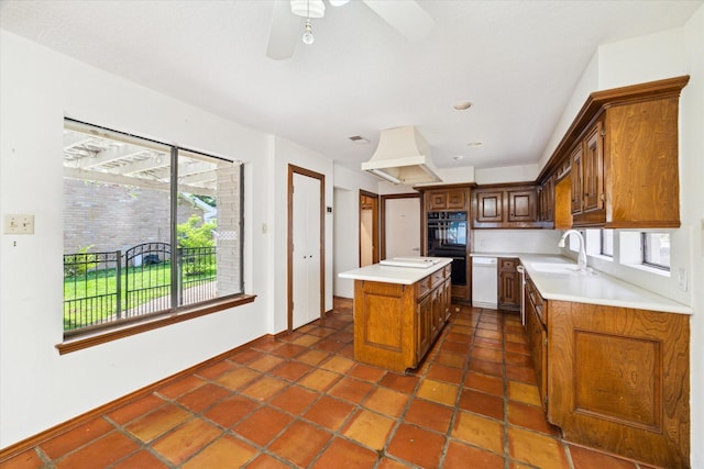 kitchen featuring light countertops, dobule oven black, a sink, and a center island