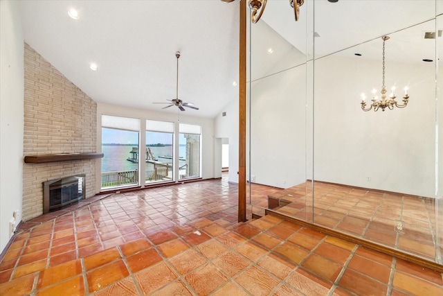 unfurnished living room featuring a brick fireplace, high vaulted ceiling, tile patterned floors, ceiling fan with notable chandelier, and a water view