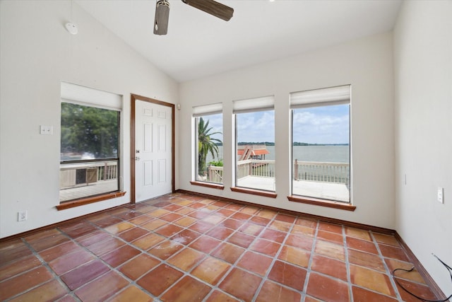 tiled empty room with a ceiling fan, baseboards, vaulted ceiling, and a wealth of natural light