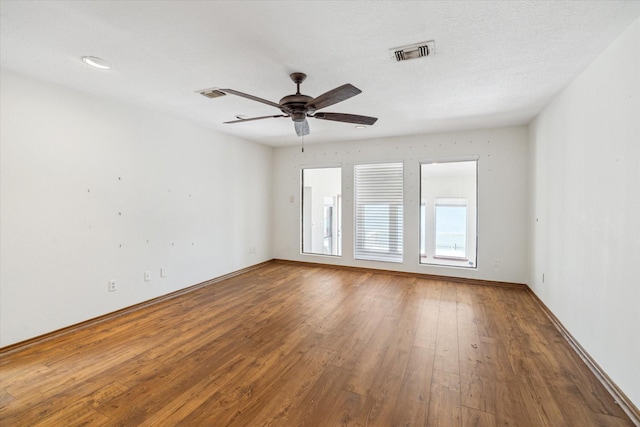 unfurnished room featuring baseboards, ceiling fan, wood finished floors, and visible vents