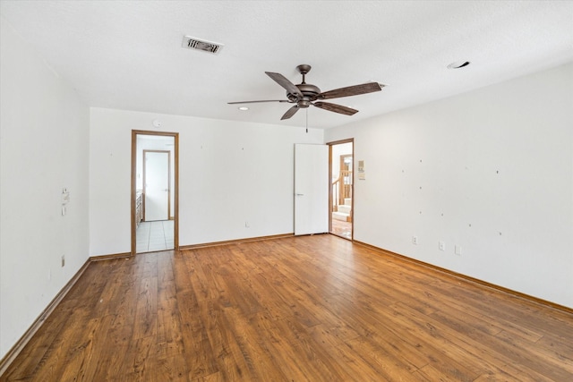 unfurnished room with visible vents, a ceiling fan, baseboards, and wood finished floors