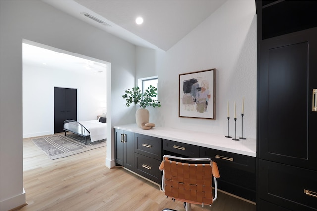 office space with light wood-style floors, baseboards, lofted ceiling, and visible vents