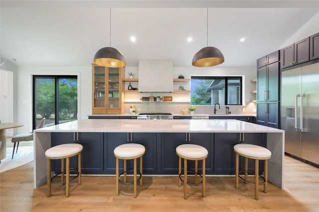 kitchen with open shelves, decorative backsplash, light wood finished floors, and built in refrigerator