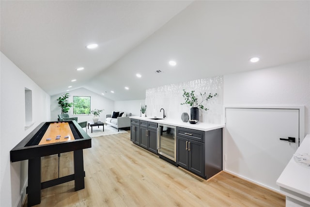 bar featuring lofted ceiling, beverage cooler, recessed lighting, a sink, and light wood-style flooring