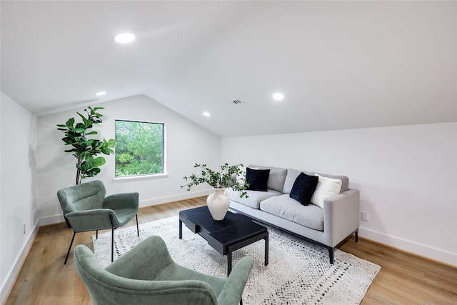 living area featuring visible vents, light wood-style flooring, baseboards, and lofted ceiling