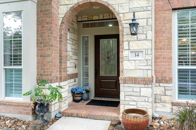 entrance to property featuring brick siding and stone siding