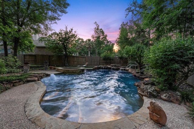 pool at dusk featuring a fenced in pool, a fenced backyard, and an in ground hot tub