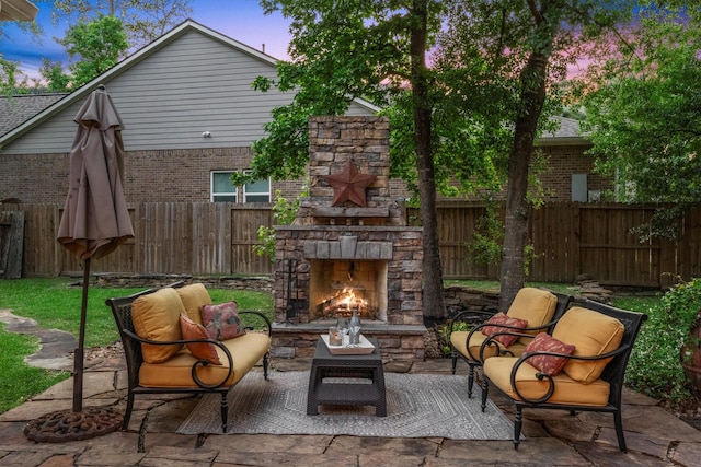 view of patio / terrace with a fenced backyard and an outdoor living space with a fireplace