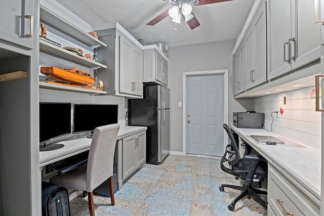 home office featuring a ceiling fan, baseboards, and built in study area