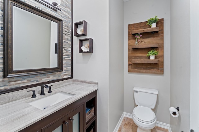 half bathroom featuring baseboards, vanity, and toilet