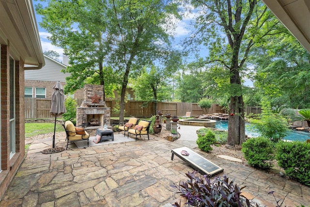 view of patio / terrace with an outdoor stone fireplace, a fenced backyard, and a fenced in pool