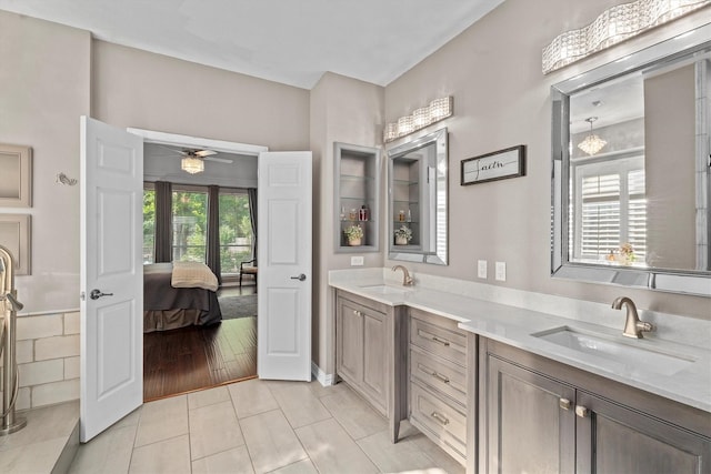 ensuite bathroom with double vanity, a sink, ceiling fan, and ensuite bath