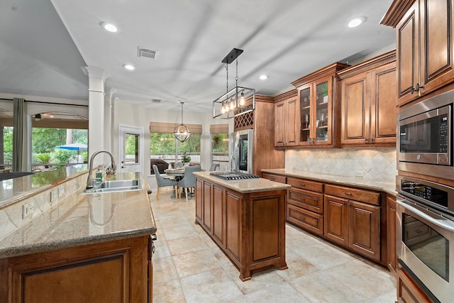 kitchen featuring visible vents, brown cabinetry, a center island with sink, a sink, and stainless steel appliances