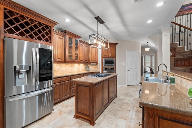 kitchen featuring appliances with stainless steel finishes, a sink, brown cabinetry, decorative backsplash, and glass insert cabinets