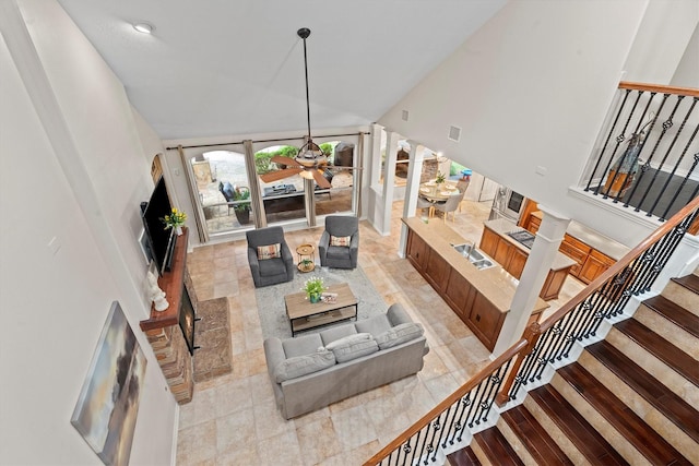 living room featuring stairway, ceiling fan, visible vents, and a towering ceiling
