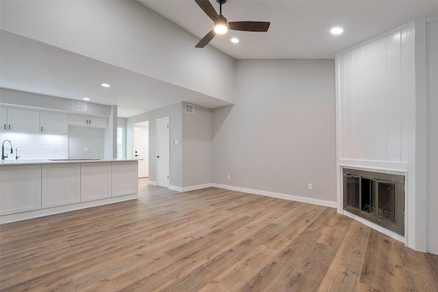 unfurnished living room with a ceiling fan, baseboards, recessed lighting, and light wood-style flooring