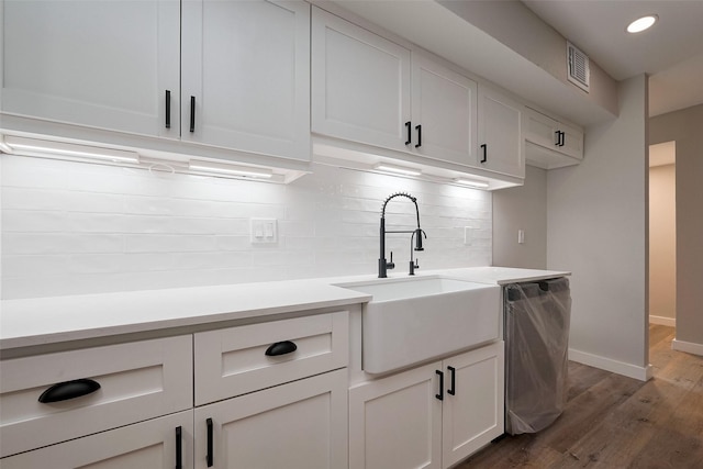 kitchen featuring a sink, decorative backsplash, stainless steel dishwasher, visible vents, and dark wood-style floors