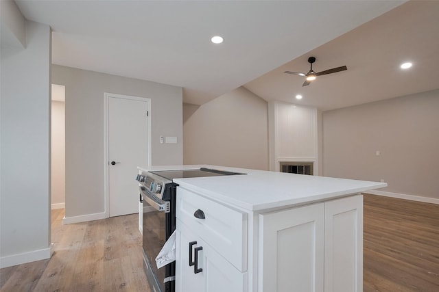 kitchen with a center island, light wood-type flooring, electric range oven, white cabinetry, and a ceiling fan