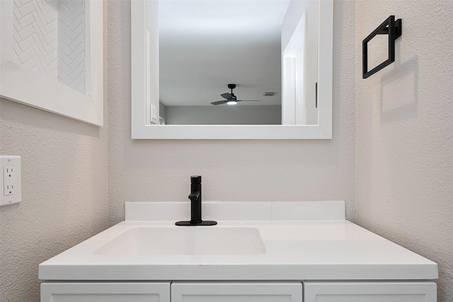 bathroom featuring vanity, a textured wall, and a ceiling fan