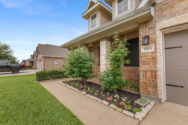 doorway to property featuring a lawn and brick siding