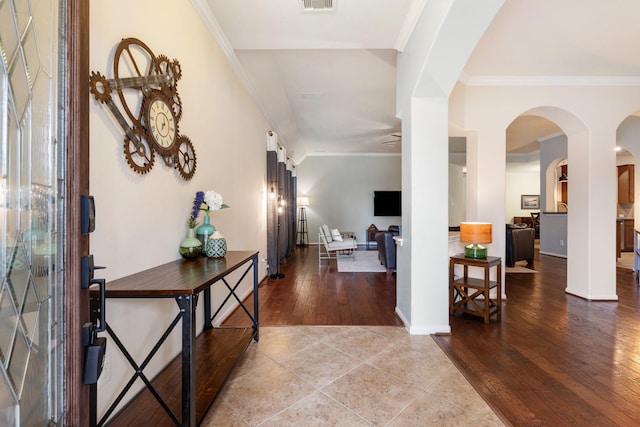 entrance foyer featuring arched walkways, ornamental molding, tile patterned floors, and visible vents
