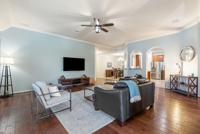 living room with arched walkways, ornamental molding, ceiling fan with notable chandelier, and dark wood-type flooring