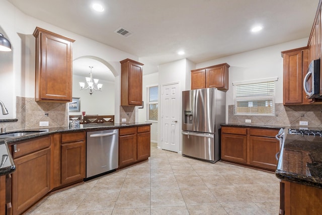 kitchen featuring appliances with stainless steel finishes, an inviting chandelier, a sink, tasteful backsplash, and visible vents