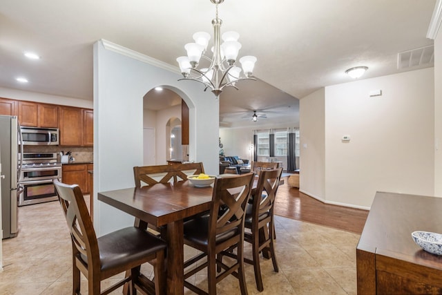 dining room featuring arched walkways, ceiling fan with notable chandelier, baseboards, light tile patterned floors, and visible vents