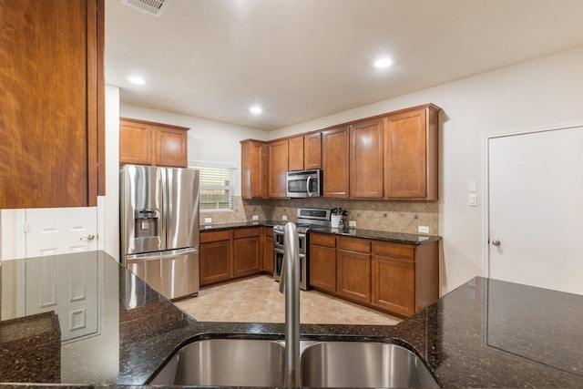 kitchen with a sink, tasteful backsplash, brown cabinets, and stainless steel appliances