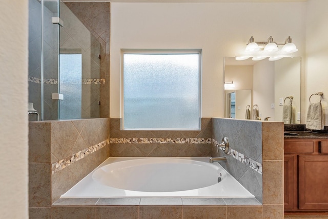 bathroom featuring vanity, a bath, and tiled shower