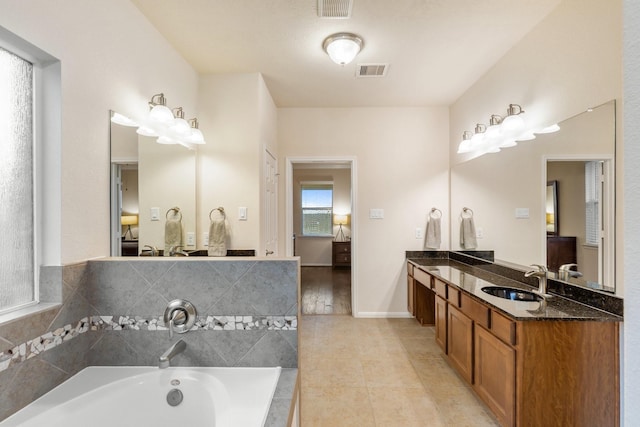 ensuite bathroom with visible vents, a sink, a garden tub, and double vanity