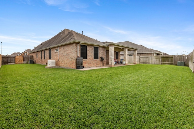 back of house featuring a lawn, brick siding, a patio, and a fenced backyard