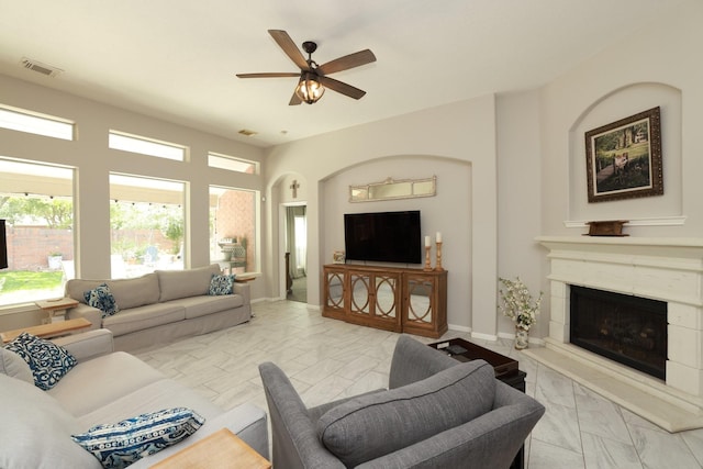 living area featuring light marble finish floors, a ceiling fan, and a high end fireplace