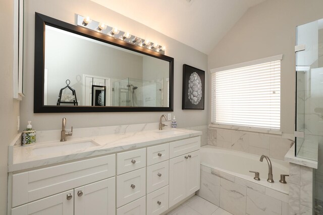 full bathroom featuring vaulted ceiling, a stall shower, a bath, and double vanity