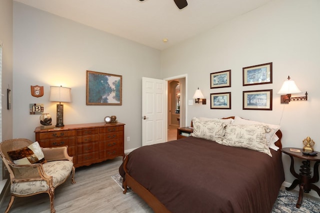 bedroom featuring light wood finished floors, arched walkways, baseboards, and a ceiling fan