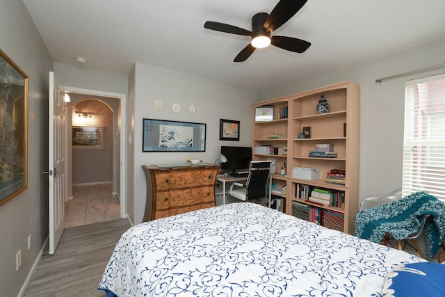 bedroom with arched walkways, baseboards, and ceiling fan