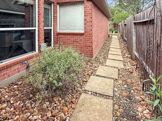 view of side of home with brick siding and fence