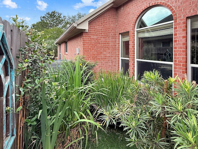 view of side of property with brick siding and fence