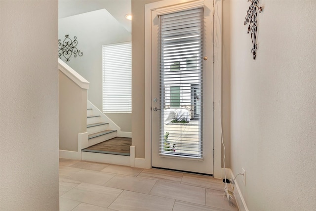 doorway with tile patterned flooring, baseboards, and stairway