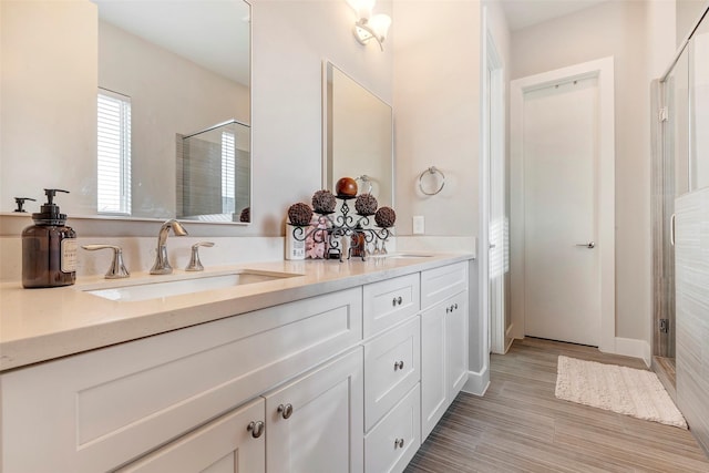 bathroom featuring double vanity, a shower stall, and a sink