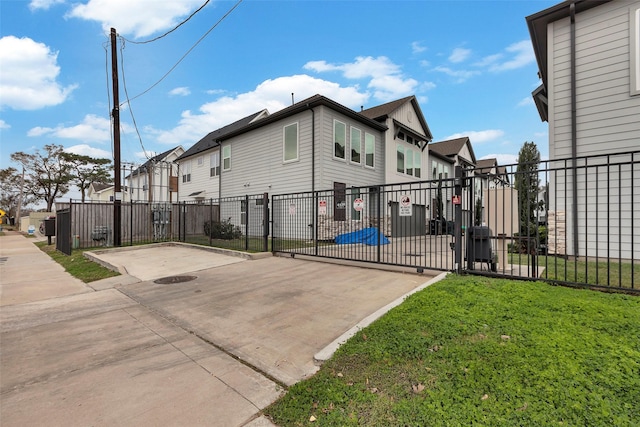 exterior space with fence, a gate, a lawn, and a residential view