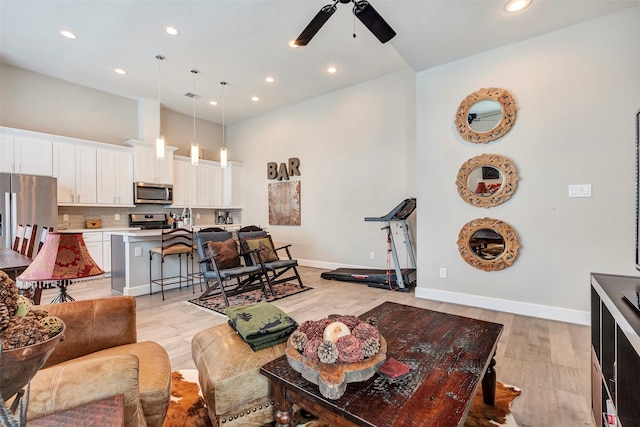 living area with recessed lighting, a ceiling fan, light wood-style floors, and baseboards