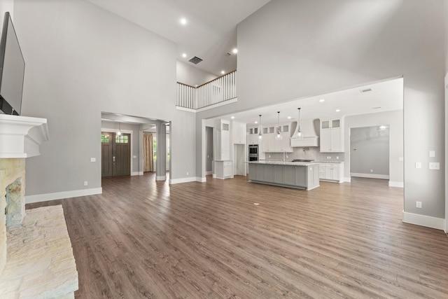 26111 Upper Beacon Pl, Montgomery, TX 77316 - unfurnished living room featuring light wood-style floors, recessed lighting, baseboards, a towering ceiling, and visible vents