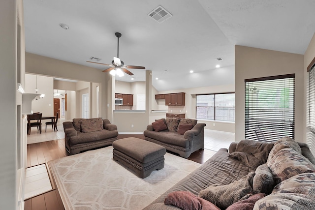 living room featuring visible vents, light wood finished floors, ceiling fan, and vaulted ceiling