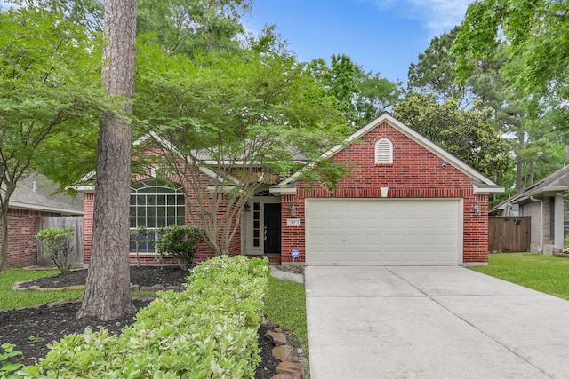 view of front facade with an attached garage, fence, brick siding, and concrete driveway