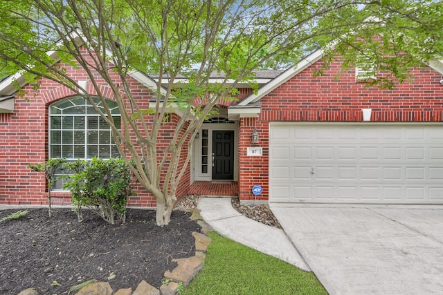 view of front of home with a garage, driveway, and brick siding